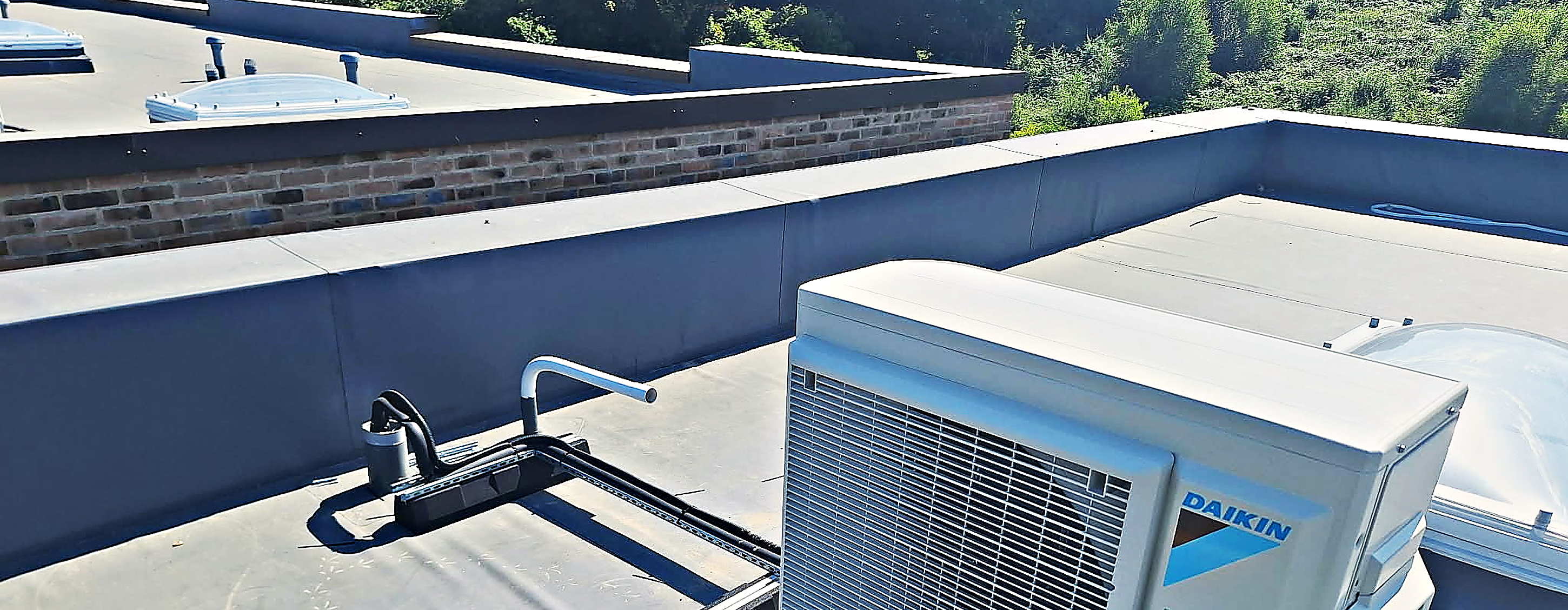 Daikin condenser unit on a flat roof with the pipework run in trunking