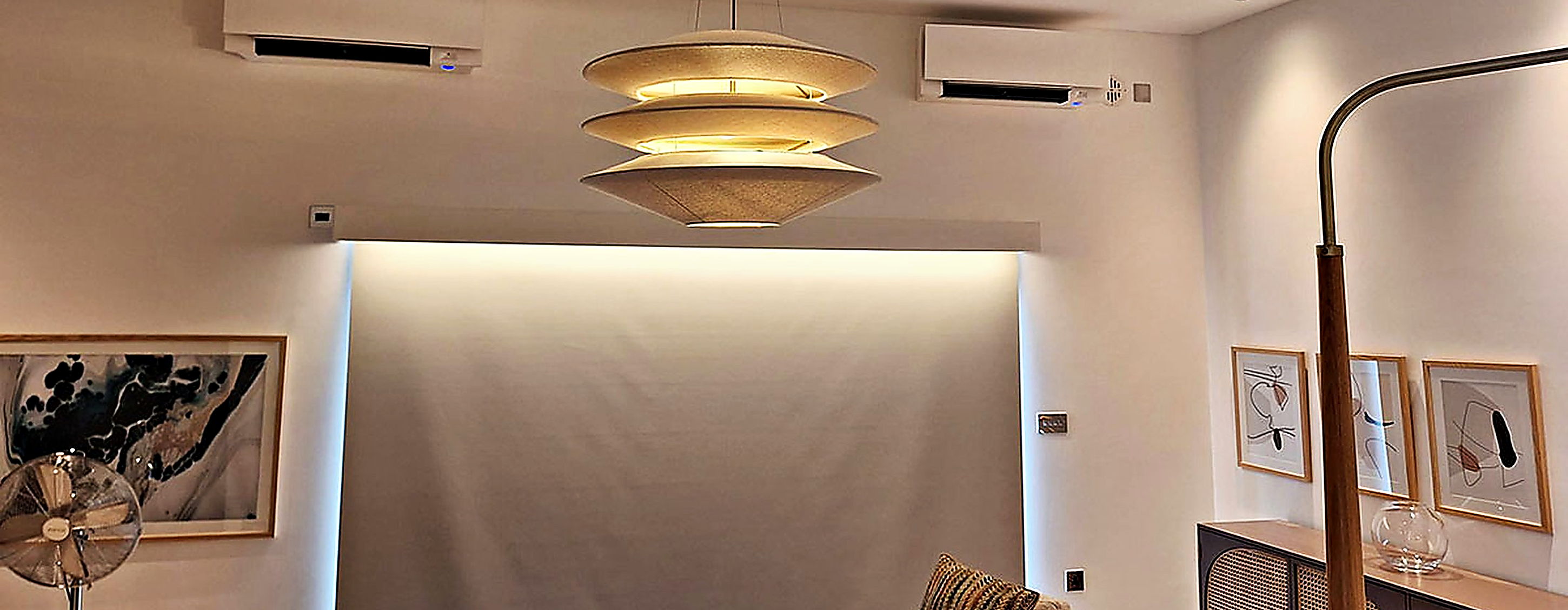 Open plan living room with two wall mounted units and a designer pendant light