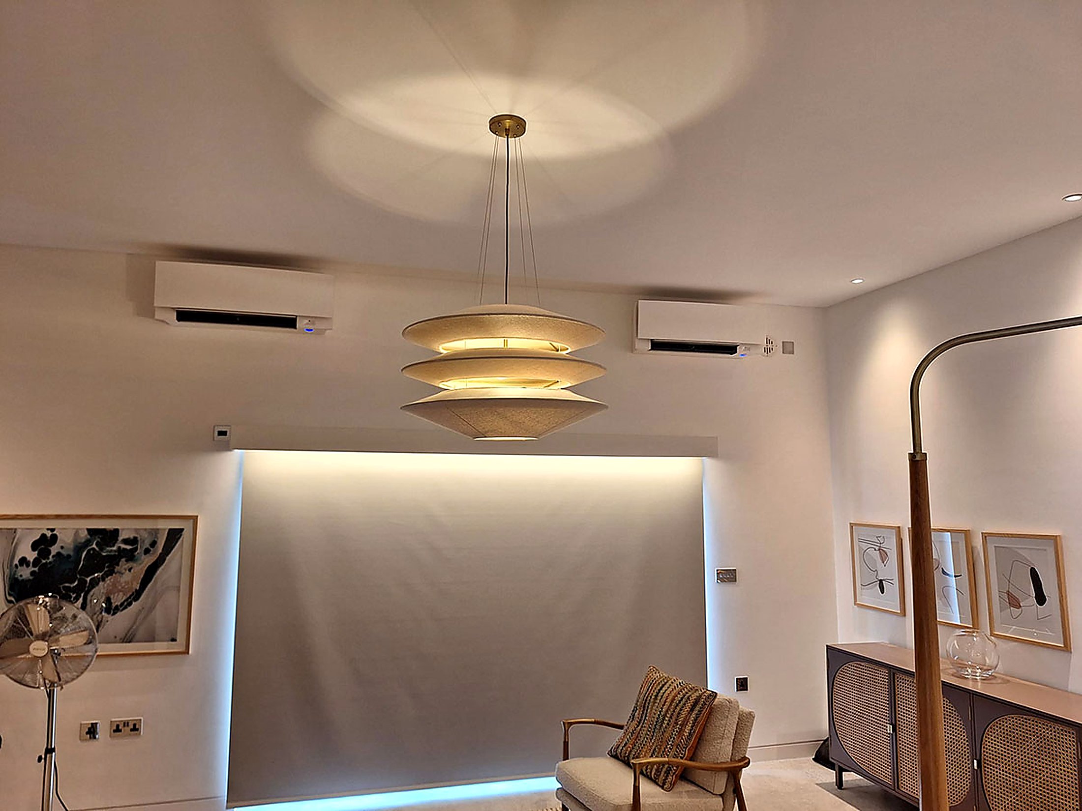 Open plan living room with two wall mounted units placed either side of a designer pendant light
