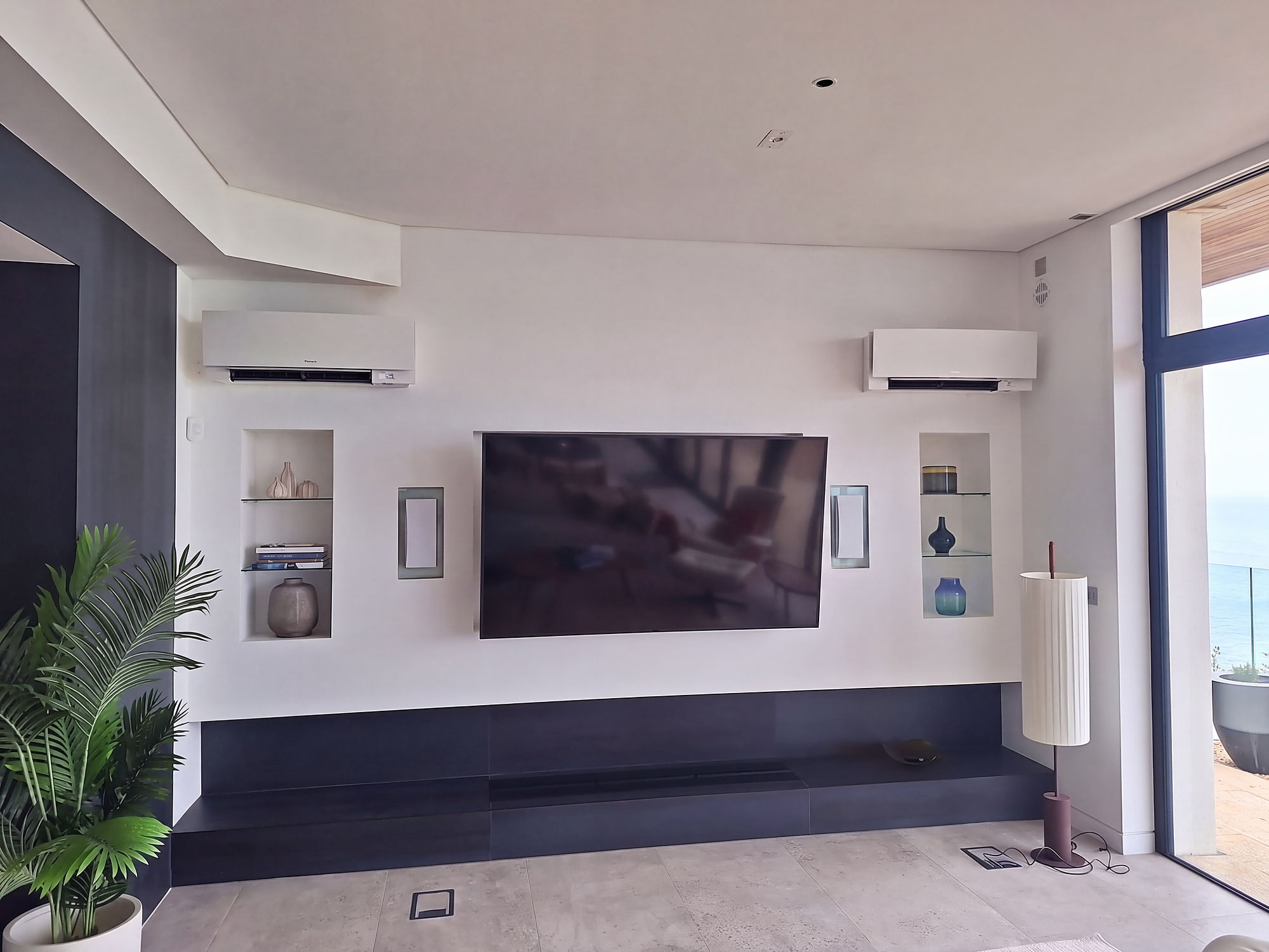 Coastal living room with two wall mounted units flanking a media wall and a sea view