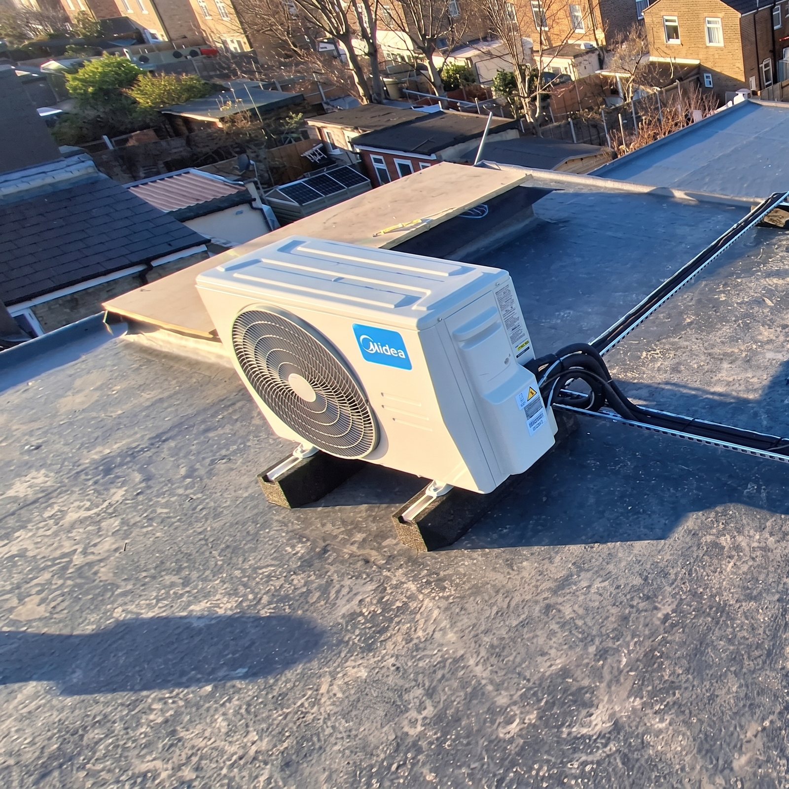 Outdoor unit on rubber feet on a flat roof, looking out over the rooftops