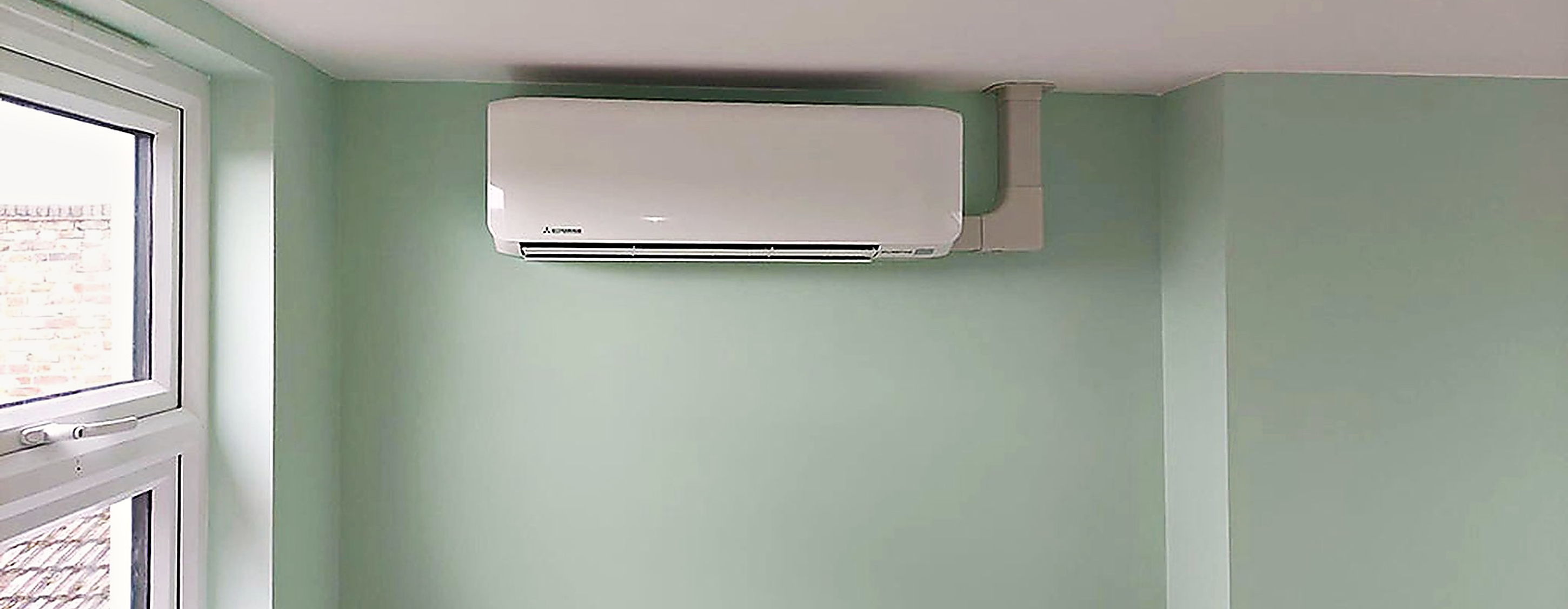 Discreet wall mounted unit high on the wall of a green painted room